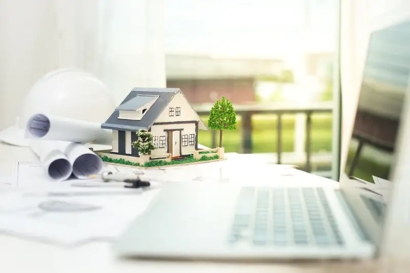 Un maquette de maison et des plans de construction, symbolisant la vente d'un bien immobilier